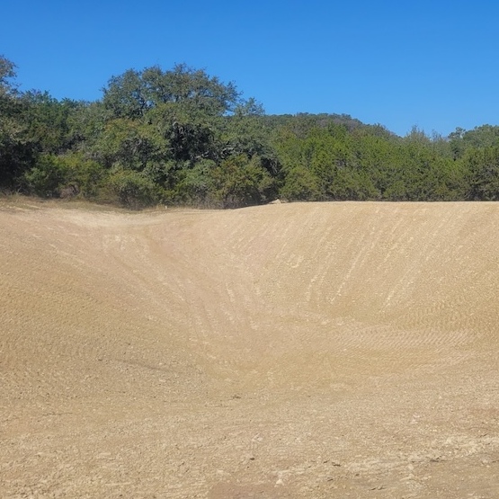 Brown earthen ditch with forest in background.