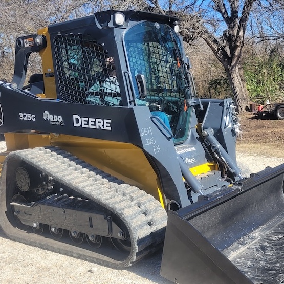 A side-view of a tractor with trees in the background.